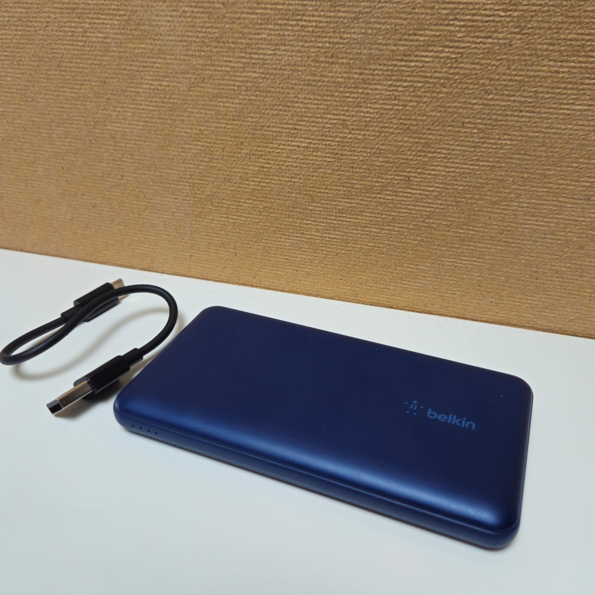 Blue Belkin power bank with an attached charging cable.