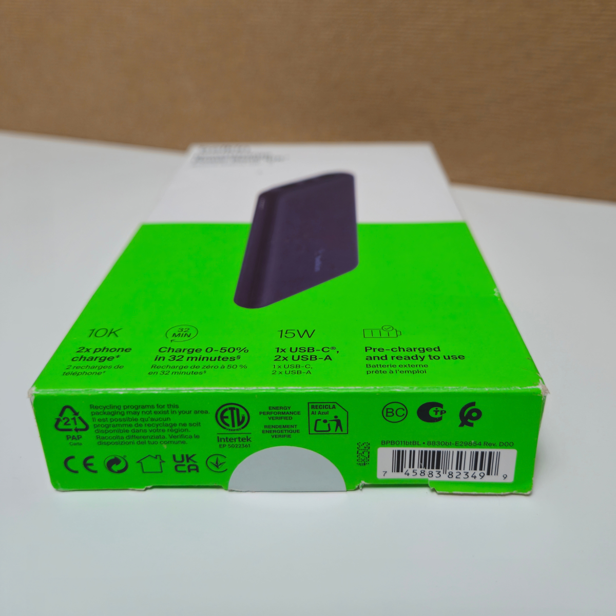 A green and white retail box for a portable power bank. The box includes text highlighting 10K charging, 15W USB-C fast charging, and 2x USB-A ports, with various certification logos along the bottom edge.