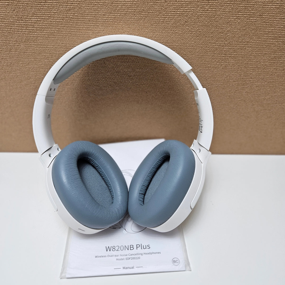 White Edifier W820NB Plus headphones with blue earcups on top of the user manual.