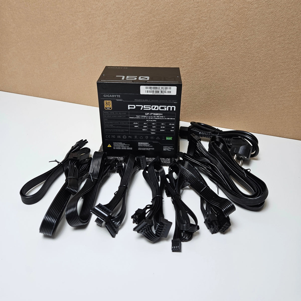 Gigabyte P750GM power supply unit displayed with all its included black flat modular cables