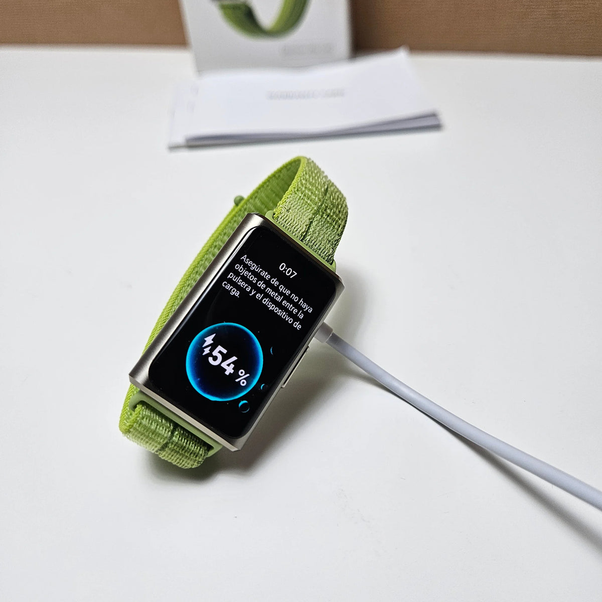Huawei Band 11 Pro connected to a white charging cable, with a 54 percent charging indicator on screen.