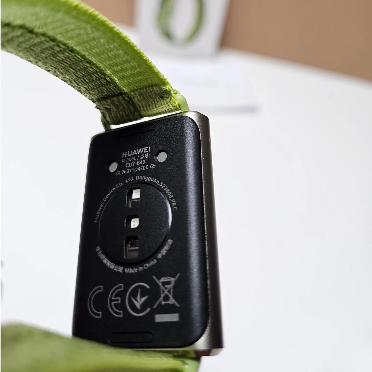 Rear close-up of Huawei Band 11 Pro showing the sensor area, charging contacts and green woven strap.