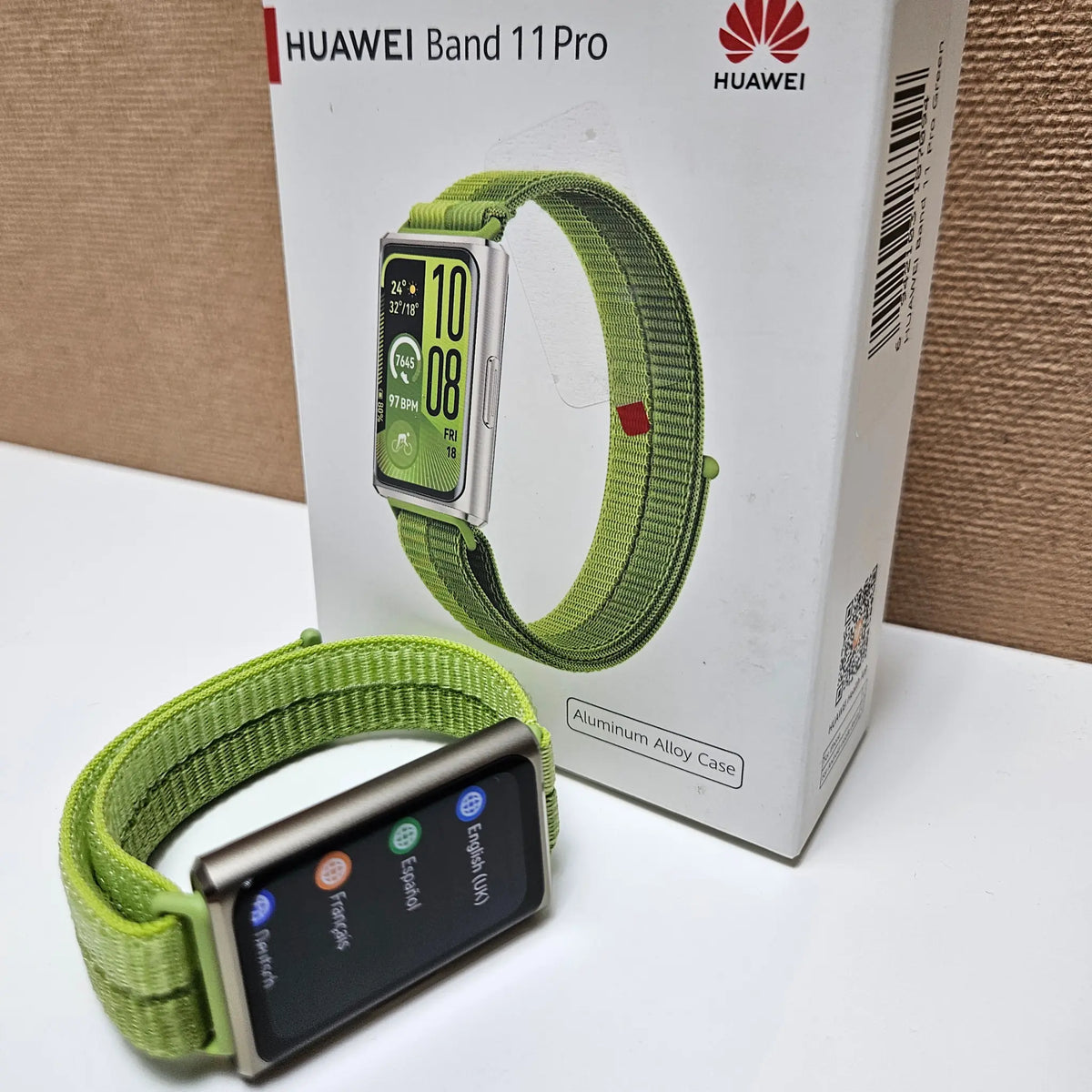 Huawei Band 11 Pro with green strap beside its retail box, with the language menu displayed.