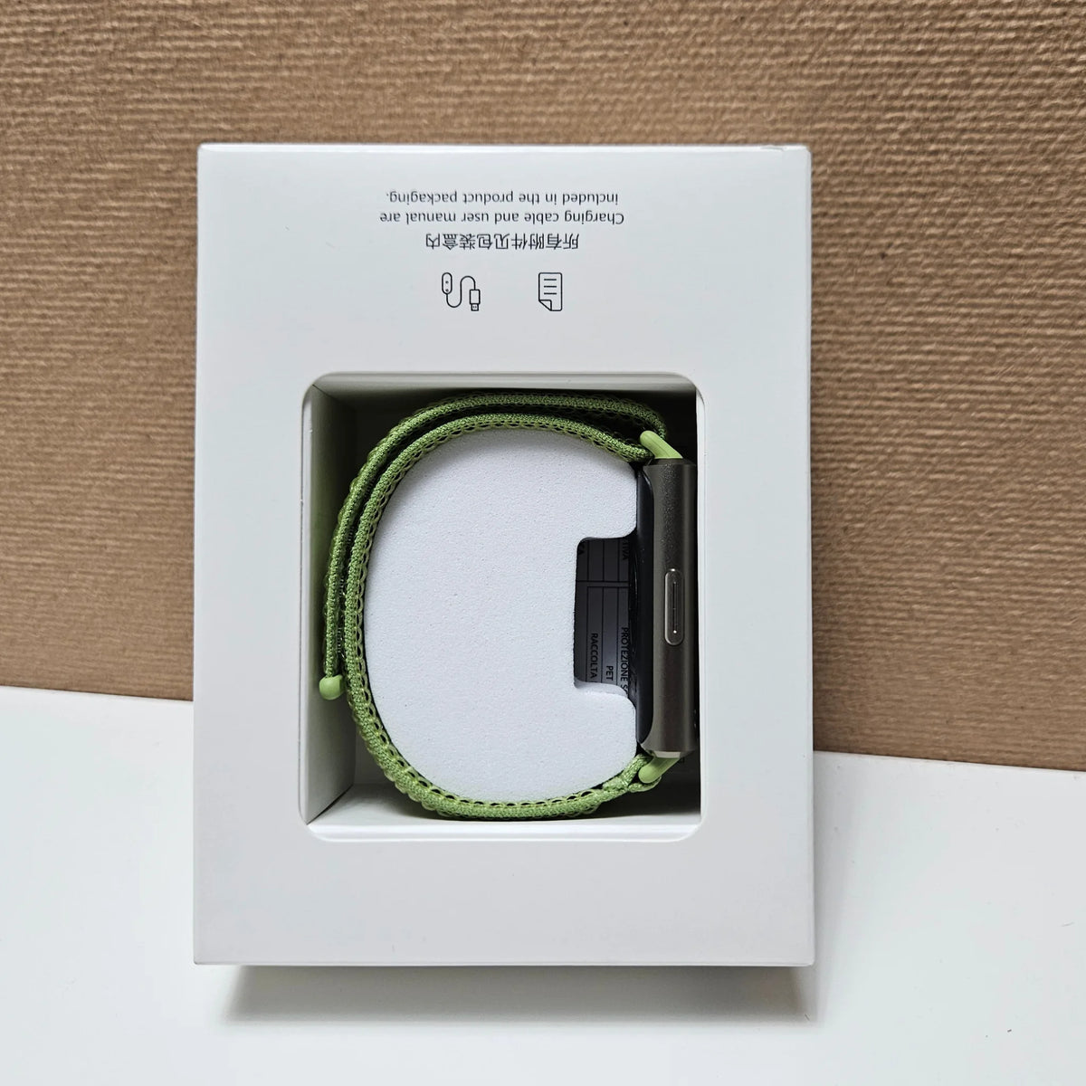 Side view of Huawei Band 11 Pro in its packaging tray, showing the green strap and case button.