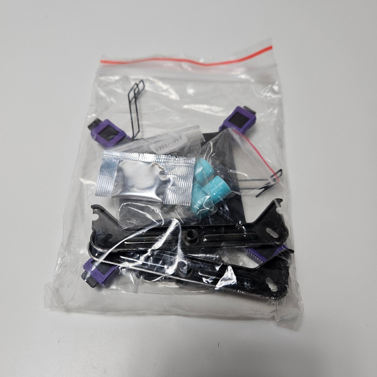 Plastic bag containing brackets, thermal paste, and screws for cooler installation
