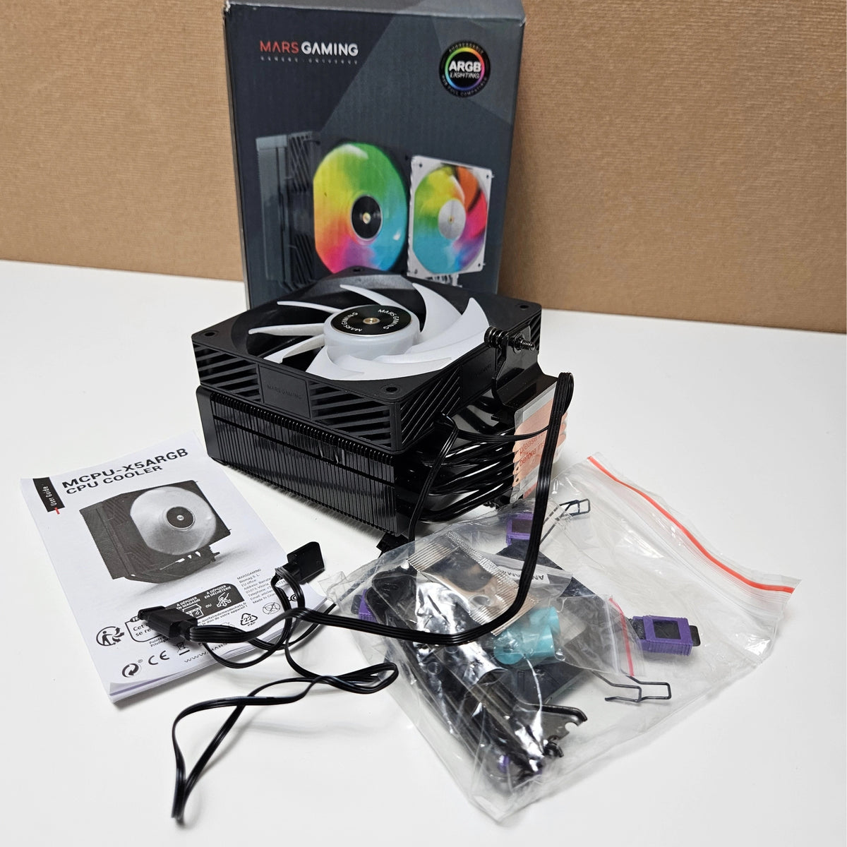 Unboxed Mars Gaming CPU cooler with its fan, user guide, and mounting accessories