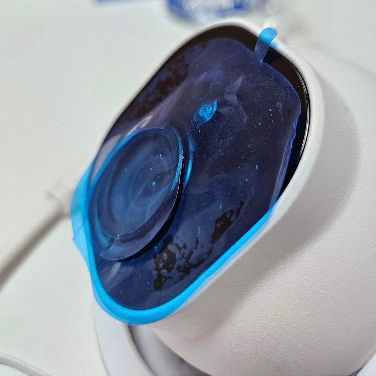 Macro shot of the Reolink camera lens covered in its original blue protective plastic film.