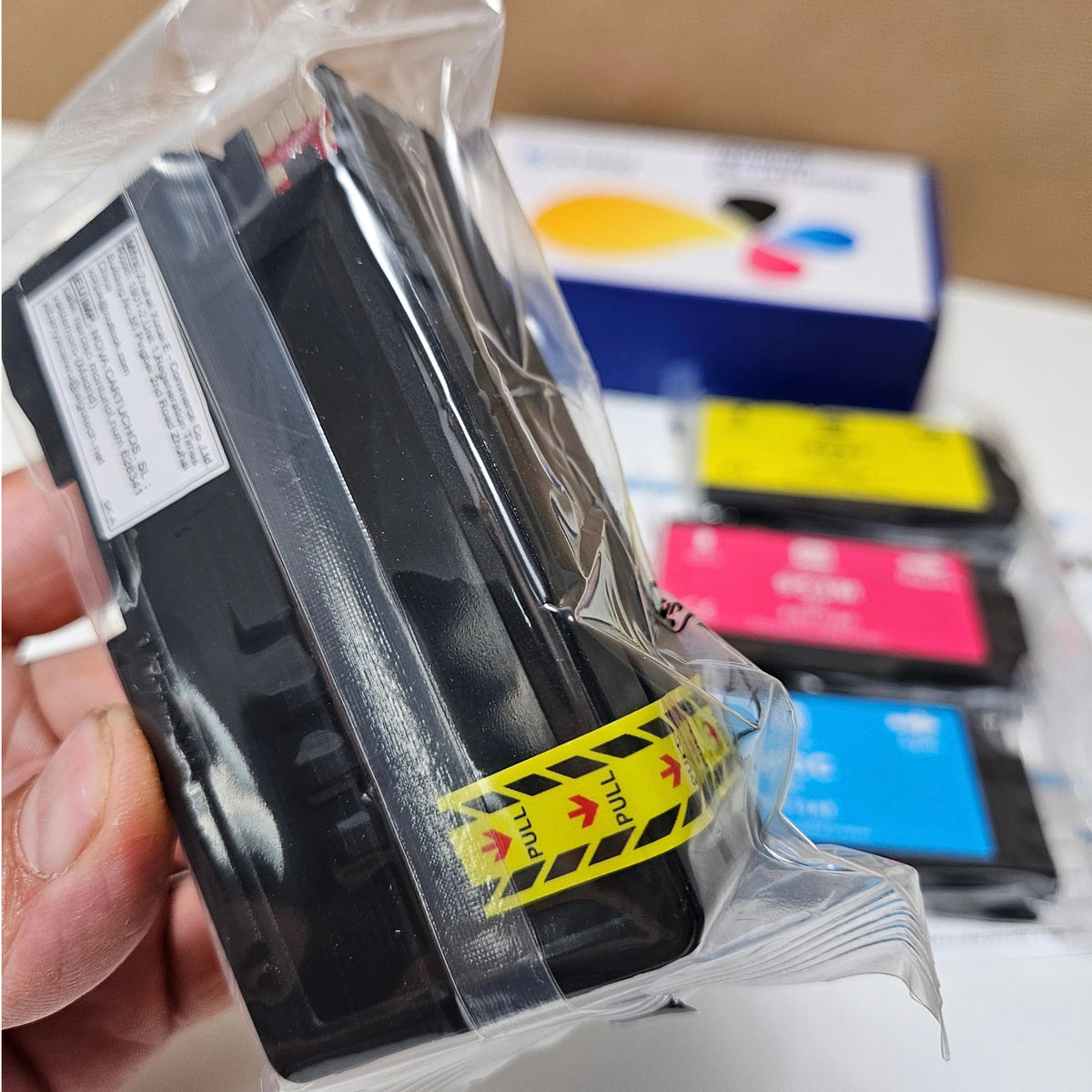 Hand holding a sealed Skydo 953XL black ink cartridge with a yellow pull tab