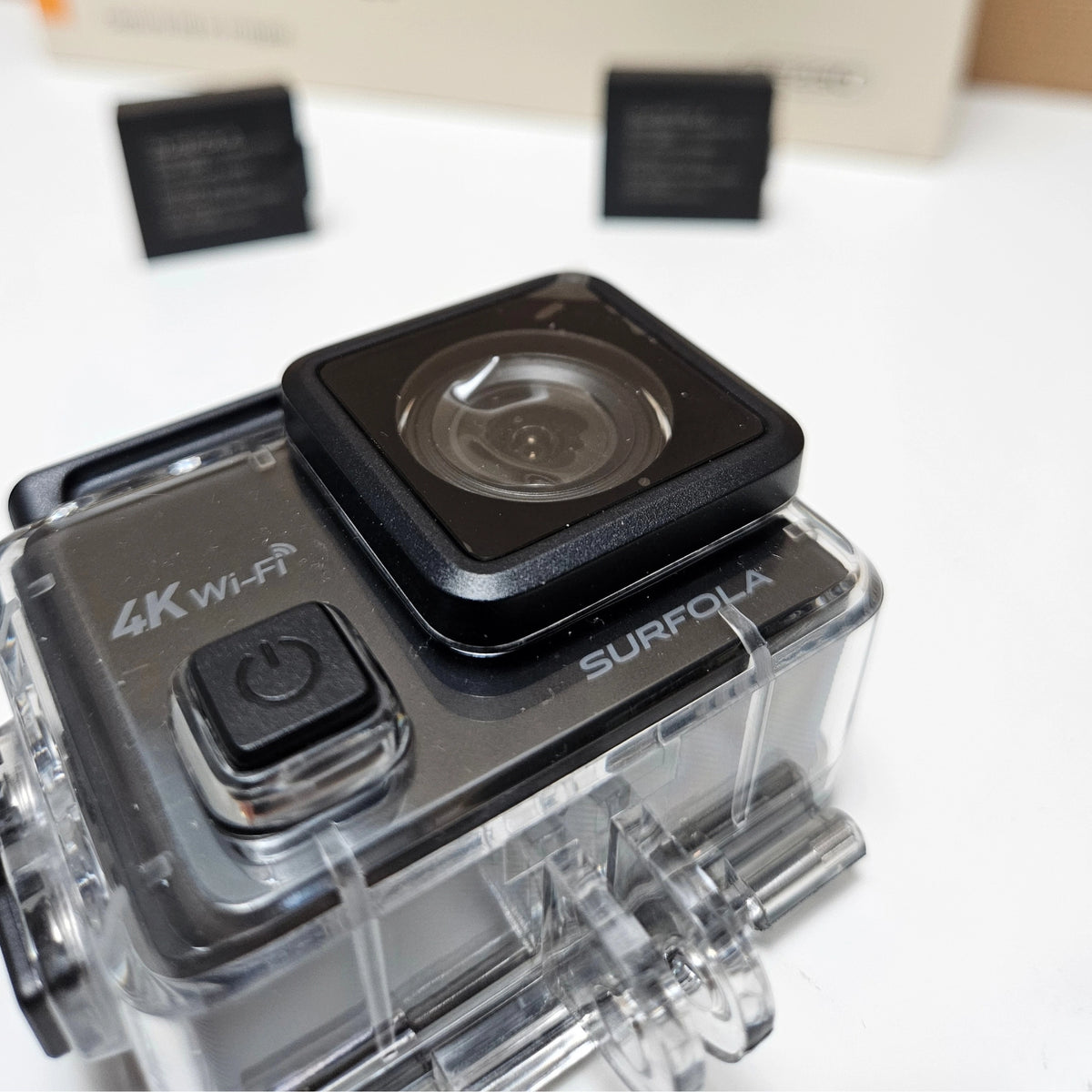 Close-up of the clean Surfola 4K action camera lens housing inside its clear case.