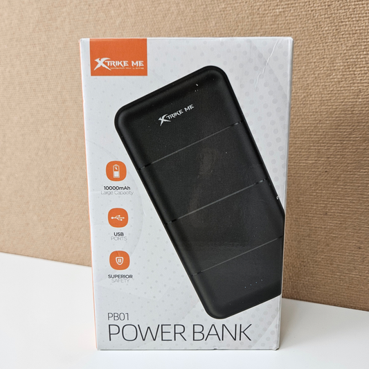 Xtrike Me PB01 Power Bank retail packaging box, showing a black power bank graphic on a white box with orange accents, set against a textured beige background.